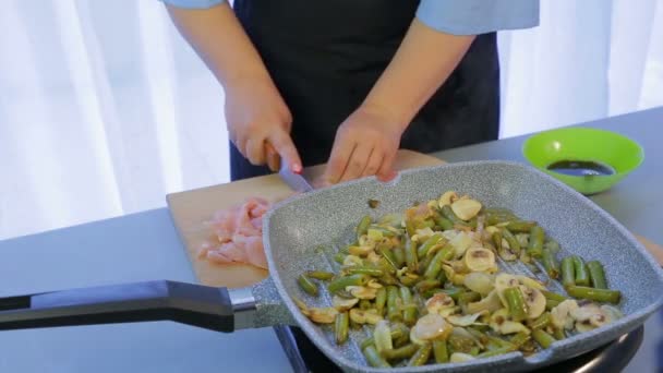 Woman cuts chicken fillet for Thai noodles with vegetables. — Stock Video