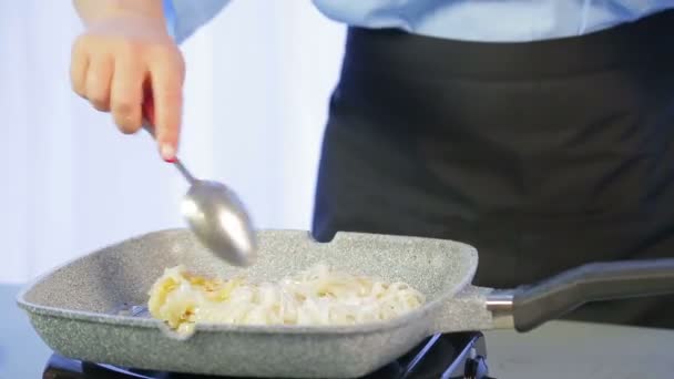 Uma mulher está misturando macarrão de arroz em uma frigideira com uma espátula de madeira . — Vídeo de Stock