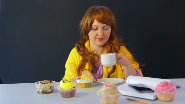 Het meisje in een café aan de tafel drinken thee en eten taarten — Stockvideo