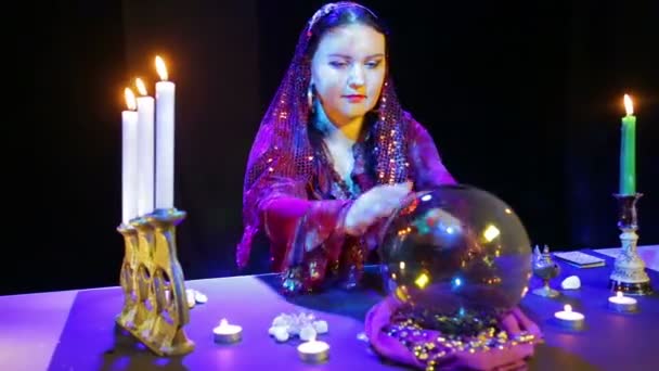 Gypsy in a red dress in a scarf reads the future in a mirror ball — Stock Video