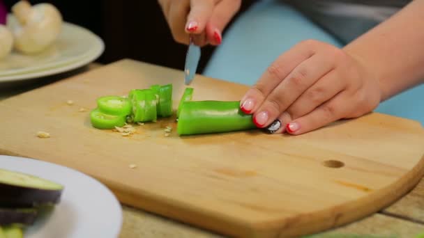 Жінка нарізає зелений довгий перець чилі ножем на дерев'яній дошці. часові кола — стокове відео