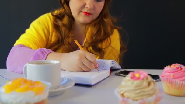 La chica en el café en la mesa escribe en el diario — Vídeo de stock