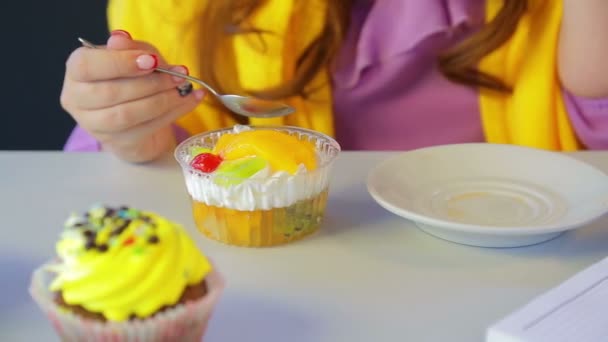 La chica en un café en la mesa bebe té y come pasteles con una cuchara — Vídeos de Stock