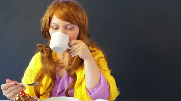Dziewczyna w kawiarni przy stole picia herbaty i jedzenia ciasta. — Wideo stockowe