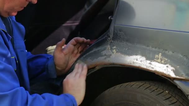Ένας άνθρωπος καθαρίζει ίχνη σκουριάς από το σώμα του αυτοκινήτου με χαρτί Έμερι — Αρχείο Βίντεο