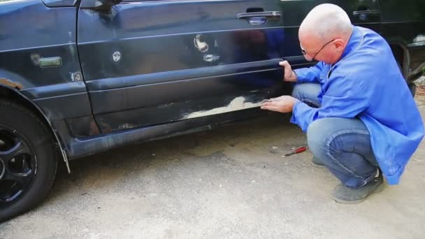 Автомобільний механік очищає сидіння іржі на кузові автомобіля . — стокове відео
