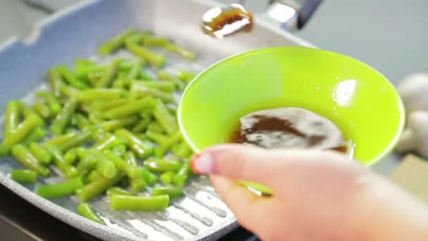 In una padella, i fagiolini vengono macinati sott'olio e mescolati con una spatola di legno. — Video Stock