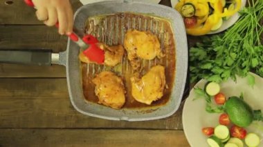 Bir ızgara tavada maşa tavuk ile karıştırma kadın el. Zaman turunda