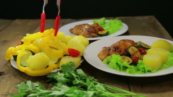Женская рука кладет ломтики овощей в тарелку с зеленым салатом и курицей . — стоковое видео
