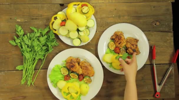 Kvinnlig hand sätter grillad kyckling och grönsaker i en tallrik med sallad. — Stockvideo