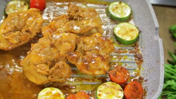 Vrouwelijke hand draait stukjes groenten met Tang en kip op een grill pan. — Stockvideo