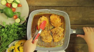 WOMANS el maşa ile bir ızgara Pan tavuk parçaları döner