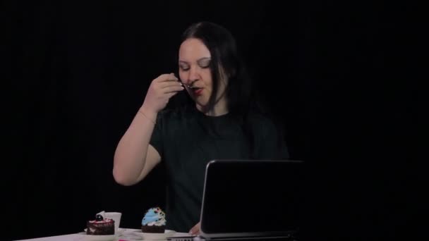 Μια γυναίκα σε ένα τραπέζι σε ένα καφέ πίνει καφέ και τρώει μια τούρτα επιδόρπιο — Αρχείο Βίντεο