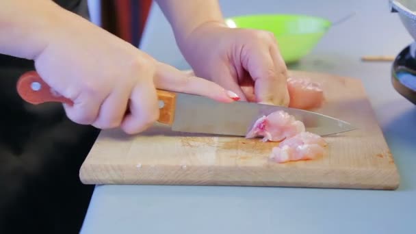 Kvinna skivor kycklingfilé med en kniv på en trä kartong. — Stockvideo