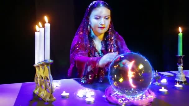 Una mujer gitana en un salón mágico está adivinando sobre una bola de cristal y un signo de euro aparece en ella — Vídeo de stock