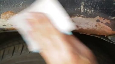 Bir adam emery kağıt ile bir arabanın arka pas temizler. Zaman turları.