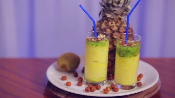 Bicchieri con frullato di frutta su un piatto bianco con frutta e noci ruotano in cerchio — Video Stock
