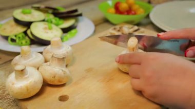 Bir kadın ahşap tahta üzerinde bir bıçak ile dilimleri içine champignon mantar pirzola. zaman Tur