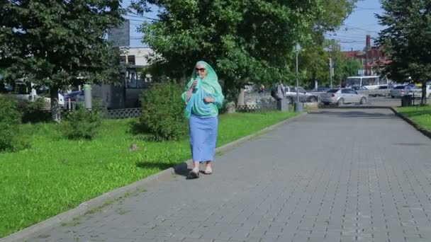 Uma jovem muçulmana em um lenço leve no parque está bebendo café . — Vídeo de Stock