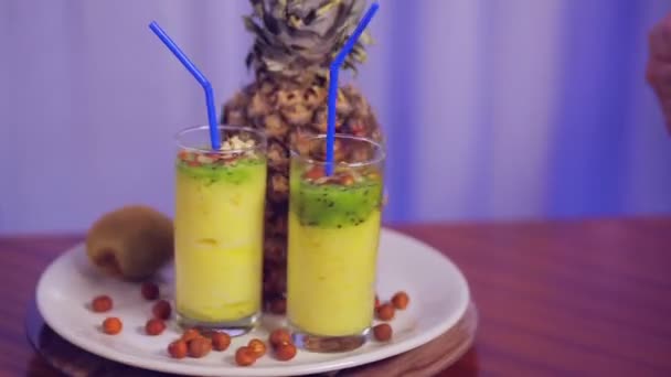Een glas met fruit smoothie op een witte plaat met fruit en noten en een gebaren klasse — Stockvideo