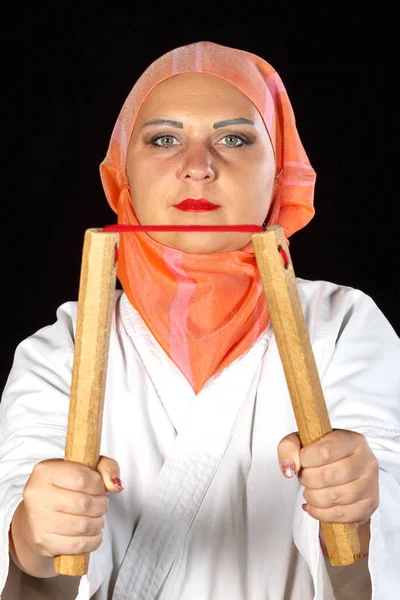 Muslimin im Kimono und Hijab im Karate-Kurs trainiert mit Nunchucks. — Stockfoto