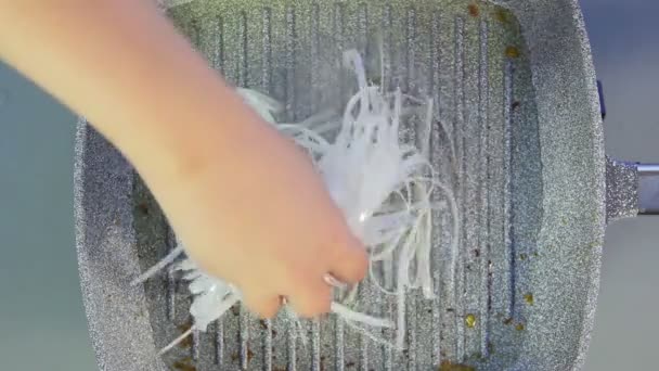 한 여성이 끓는 기름 냄비에 쌀국수를 넣습니다. — 비디오