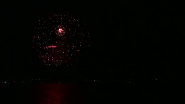 Étincelles colorées de feux d'artifice festifs dans le ciel nocturne au-dessus de la rivière se reflétant dans l'eau. Laps de temps 