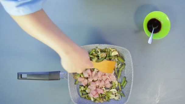 La femme ajoute des morceaux de poulet à la casserole avec des haricots verts et des champignons — Video