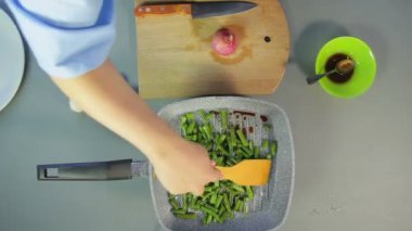 Ahşap bir spatula ile tavada kavurma yeşil fasulye karıştırma Kadın