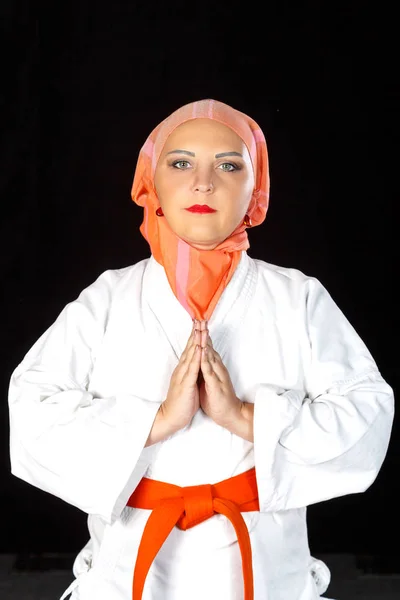 年轻的穆斯林妇女穿着和服和头巾在空手道训练黑色背景。拍摄特写. — 图库照片