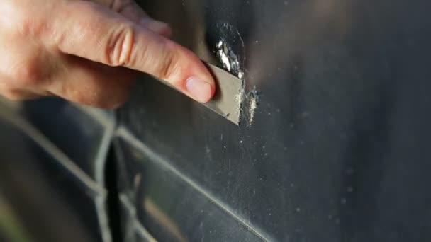 Człowiek czyści rdzę na samochodzie z skrobaczką. Czas okrążeń. — Wideo stockowe