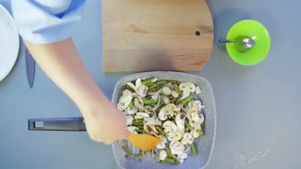 Een vrouw mengt bonen en UI met sojasaus in een pan met een houten spatel. Tijd ronden — Stockvideo