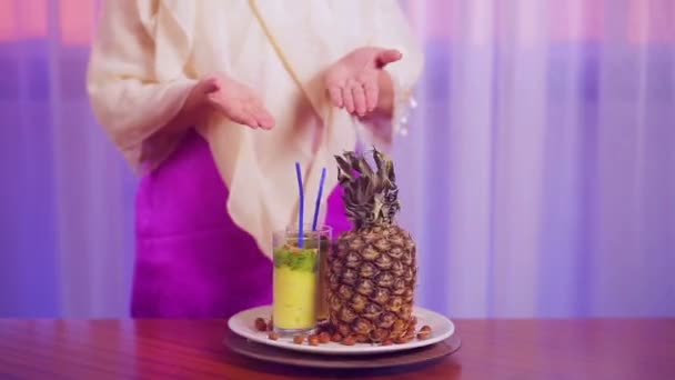 Uma mulher mostra um copo com um coquetel de frutas girando em um círculo — Vídeo de Stock