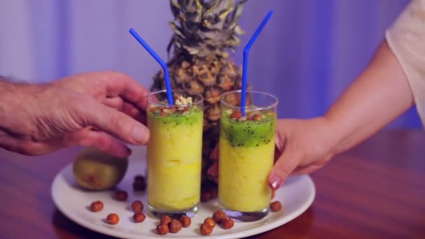Um homem e uma mulher tomam copos com suco de frutas de um prato branco — Vídeo de Stock