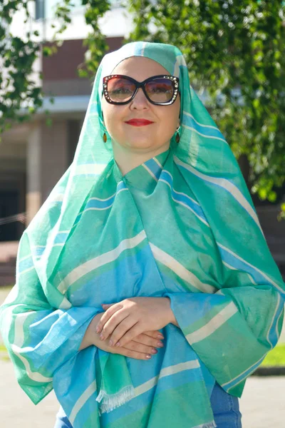 Eine junge muslimische Frau mit hellem Schal und Brille auf der Straße. — Stockfoto