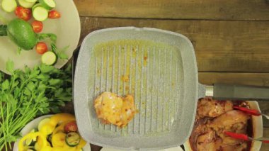 Dişi el ızgara tavasına tavuk parçaları koyar