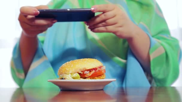 A woman in a cafe photographs on the phone a burger — Stock Video