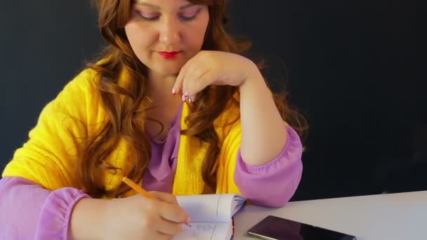 Дівчина в кафе за столом пише в щоденнику — стокове відео