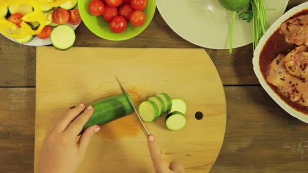 Female hand prunes zucchini rings on a wooden board. — Stock Video