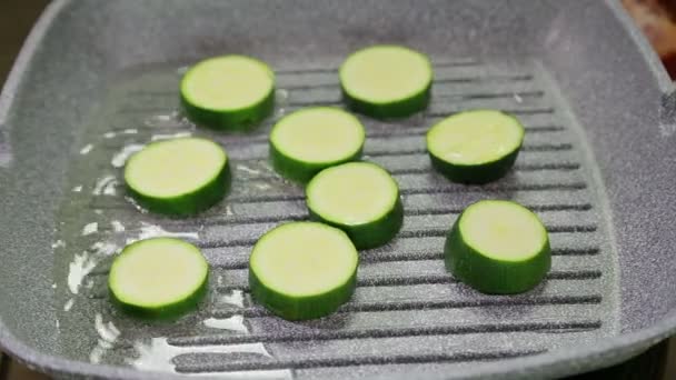 As abobrinhas verdes fritam-se na manteiga em uma panela de grelha — Vídeo de Stock