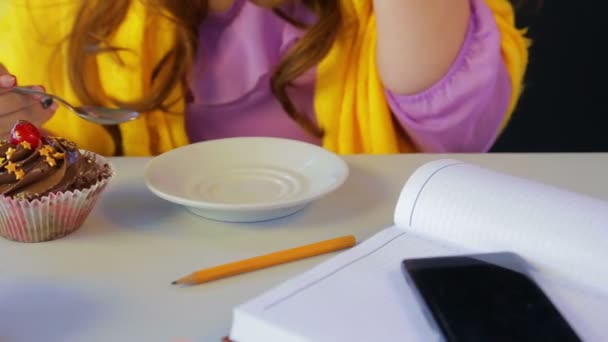 Дівчина в кафе за столом п'є зелений чай і їсть торт з ложкою — стокове відео