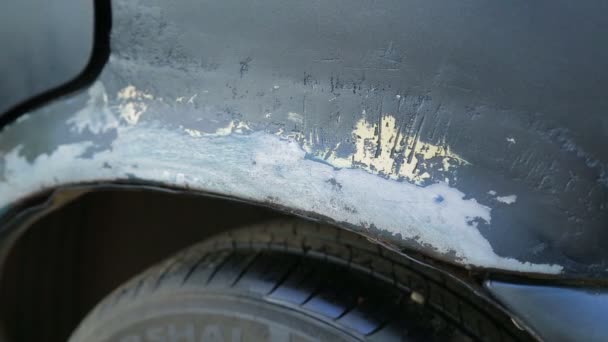Un hombre pone pintura en aerosol en las partes oxidadas de la carrocería del coche. Vueltas de tiempo — Vídeo de stock