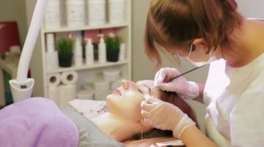 Güzellik uzmanı müşteriyi özel bir fırçayla kaşile boyar.