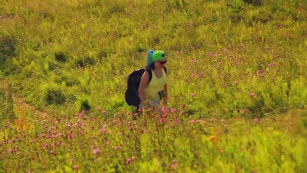 어깨와 쌍안경에 배낭을 두르고 언덕을 오르는 여성 등산객 — 비디오