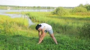 Esmer kadın sabah gölde germe egzersizleri yapıyor