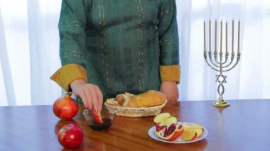 Yahudi bir kadın bir elma bir dilim alır ve Rosh Hashanah için bal batırır