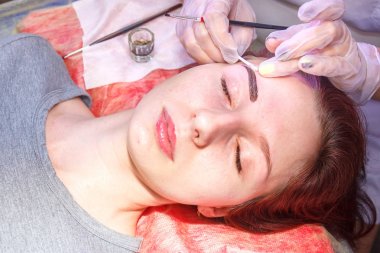 Beautician bir kına fırçası ile müşterinin kaşları lekeler.