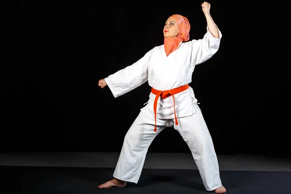 Young muslim woman in kimono and hijab in karate training over black background — Stock Photo, Image