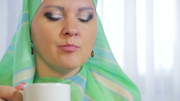 一个年轻的穆斯林妇女在咖啡馆里戴一条浅围巾 吃蛋糕和喝茶 — 图库视频影像