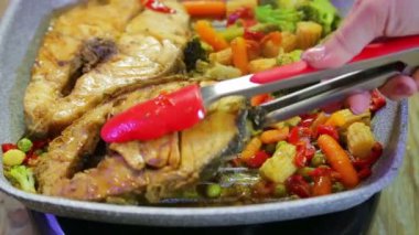 Dişi el spagetti ile bir tabak ta balık bir parça koyar.